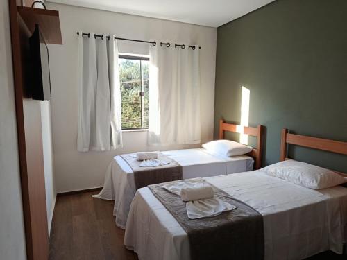 zwei Betten in einem Zimmer mit Fenster in der Unterkunft Pousada Ebenézer de Cordeiro rj in Cordeiro