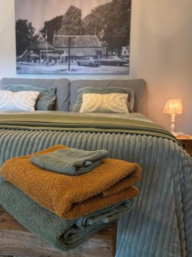 a bed with a pile of towels on it at Bij Hilma in Eext