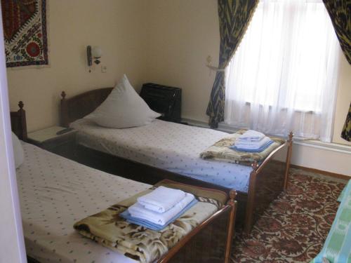 two twin beds in a room with a window at Hotel Nazira & Azizbek in Bukhara