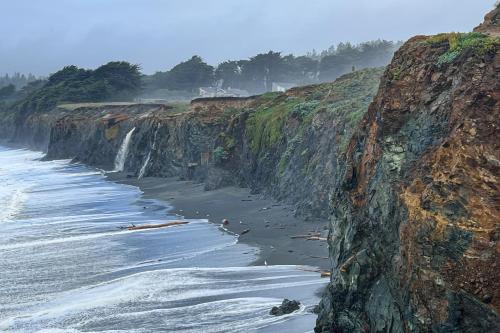 a view of a beach with a waterfall and the ocean at Cypress Cove in Sea Ranch