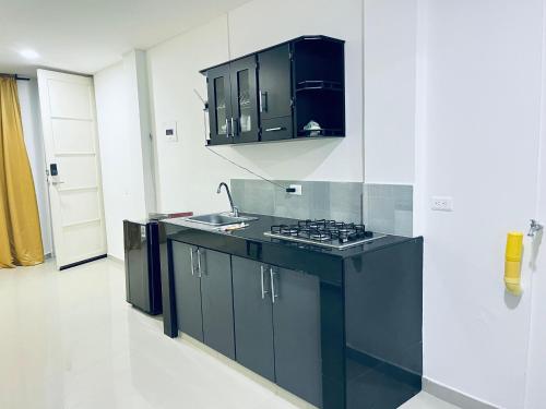 a kitchen with black cabinets and a stove top oven at Aparta Hotel Nini Cali in Cali