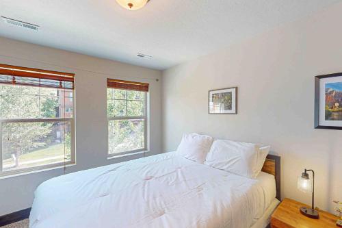 a bedroom with a white bed and two windows at Happy Tails Hideout in Kamas
