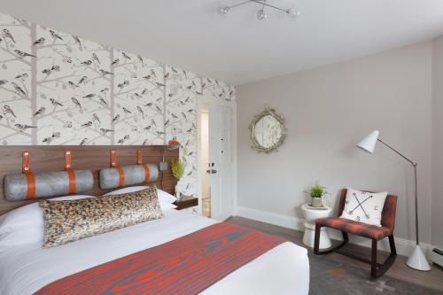 a bedroom with a bed and a chair at Field Guide Lodge in Stowe
