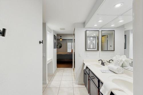 a white bathroom with two sinks and a mirror at Sunny Palm Springs Oasis Getaway in Palm Springs
