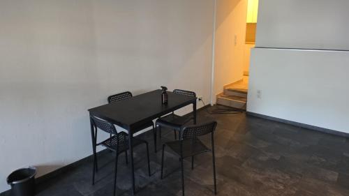 a black table with chairs and a refrigerator in a room at Sweet Ferien & Monteurs Appartement in Wuppertal