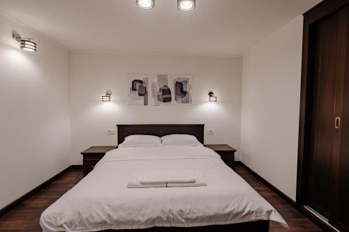 a white bedroom with a large bed with white sheets at AllEia rooms in Sebeş