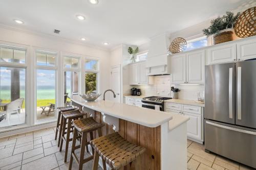 a kitchen with white cabinets and a large island with bar stools at Always On My Mind by 30A Escapes in Seacrest