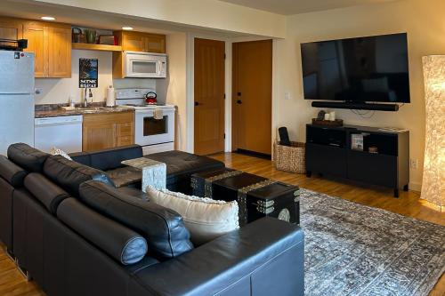 a living room with a black leather couch and a kitchen at Rose's Reach - Rosario in Eastsound