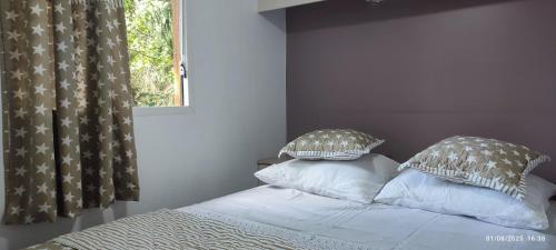 a bedroom with a bed with pillows and a window at domaine le lanis le refuge de Ambre in Saint-Girons