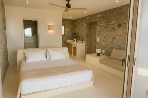 a bedroom with a bed and a stone wall at Piperi Suites in Kithnos