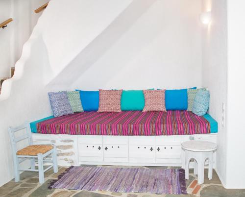 a white room with a bench with colorful pillows at Aspra Chomata Villas in Karistos