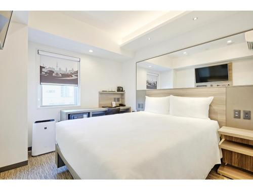 a bedroom with a large white bed and a television at Smile Hotel Sapporo Susukino Minami - Vacation STAY 60221v in Sapporo
