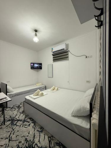 Un dormitorio blanco con una cama y un televisor. en SumayShakh Guest House, en Bukhara