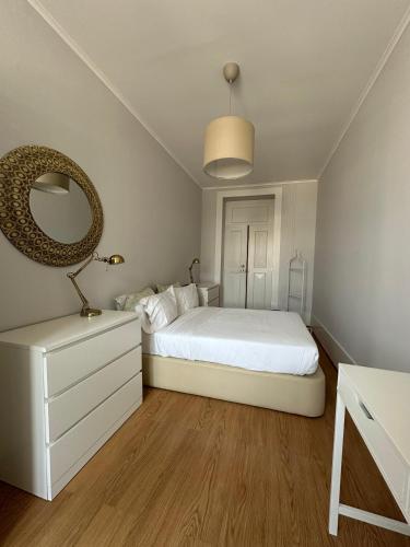 a bedroom with a white bed and a mirror at Menina da Ria Guest House in Aveiro