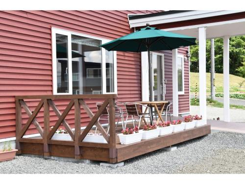 a porch with an umbrella and a table and chairs at Hotel Hanafuji Inn - Vacation STAY 82410v in Nakafurano