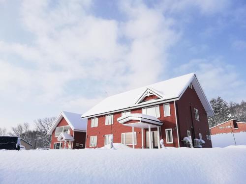 a red house with snow on the roof at Hotel Hanafuji Inn - Vacation STAY 82522v in Nakafurano