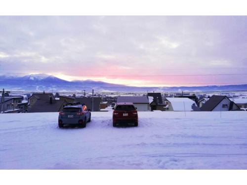 two cars parked in the snow in a town at Hotel Hanafuji Inn - Vacation STAY 82522v in Nakafurano
