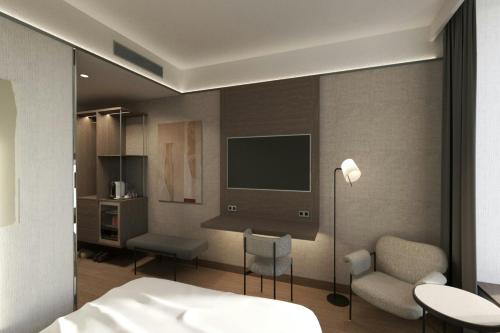 a bedroom with a bed and a tv and a chair at AC Hotel by Marriott Vilnius in Vilnius