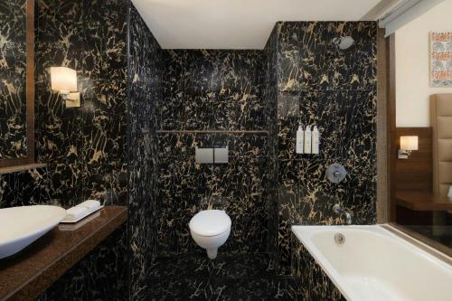 Un baño con bañera, inodoro y lavabo. en Trinity Whitefield Bengaluru, en Bangalore