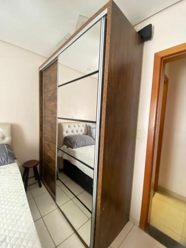 a mirror in a bedroom with a bed in it at Apartamento lindo aconchegante com garagem in Itabira