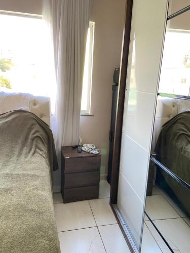 a bedroom with a mirror next to a bed at Apartamento lindo aconchegante com garagem in Itabira