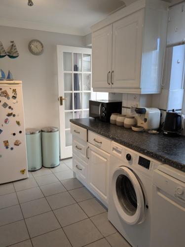 a kitchen with a washing machine and a refrigerator at Airy coastal courtyard house in Parkstone