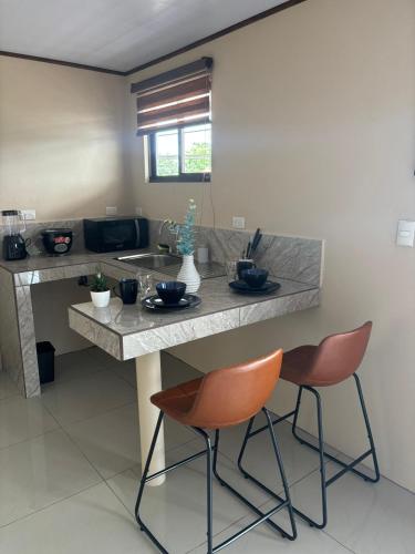a kitchen with two orange chairs and a counter at Hotel Nativo Arenal in Fortuna