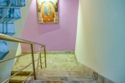 a staircase with a painting on a pink wall at Hotel O S&h Residency Bahadalpur Railway Station in Khandagiri