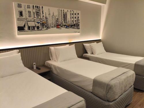 a hotel room with two beds and a picture on the wall at Hotel 28 Embu das Artes in Embu