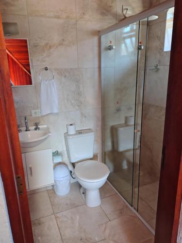 a bathroom with a toilet and a shower and a sink at Casa do Trem Suítes in Campos do Jordão