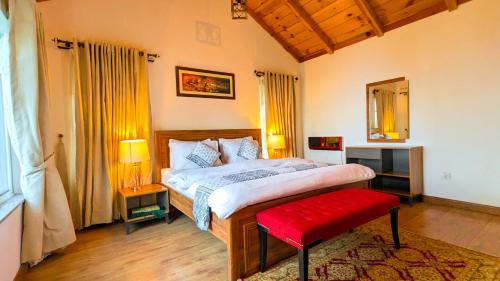 a bedroom with a large bed and a red bench at Haven Lodge Khaira Gali - Pine Ridge Residences #7 in Khaira Gali