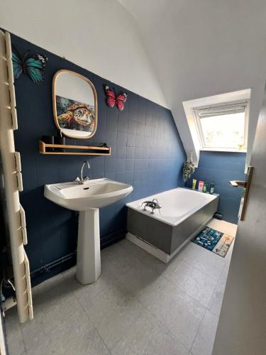 a bathroom with a sink and a bath tub and a mirror at Vue mer exceptionnelle-Appartement cosy à Erquy in Erquy
