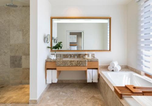 a bathroom with a tub and a sink and a mirror at Fairmont Mayakoba in Playa del Carmen