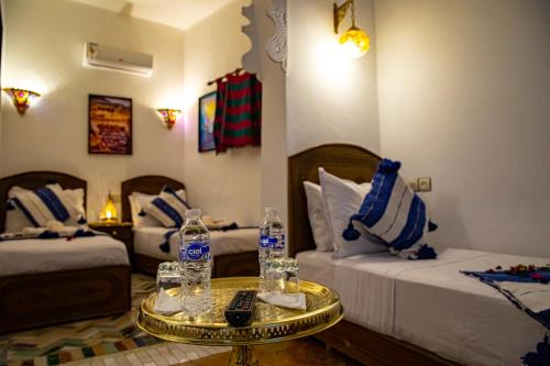 a hotel room with two beds and a table with water bottles at Riad Hikaya - Fes Story in Fès