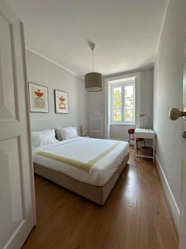 a white bedroom with a large bed and a window at Menina da Ria Guest House in Aveiro