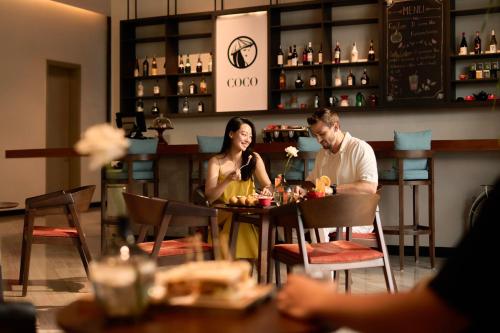 a man and woman sitting at a table in a restaurant at voco Ma Belle Danang by IHG in Da Nang
