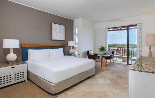 a bedroom with a large white bed and a balcony at Fairmont Mayakoba Riviera Maya - All Inclusive in Playa del Carmen