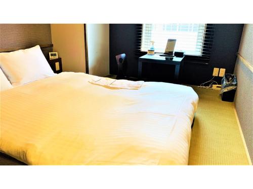 a bedroom with a large white bed with a desk at Smile Hotel Nagoya Sakae - Vacation STAY 66752v in Nagoya