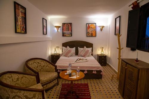 a bedroom with a bed and a table and chairs at Riad Hikaya - Fes Story in Fès