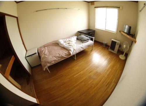a bedroom with a bed and a wooden floor at Minpakushisetsu Nipopo - Vacation STAY 19565 in Fukagawa