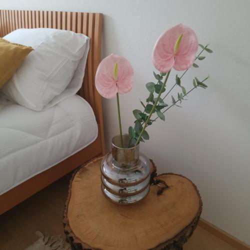 two pink flowers in a vase on a table at Porvoo Central Apartment in Porvoo