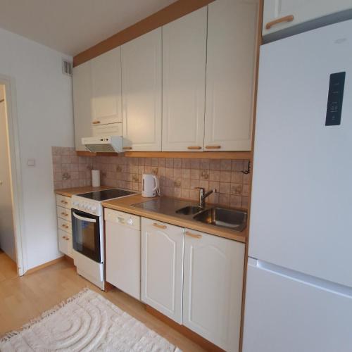 a kitchen with white cabinets and a sink and a refrigerator at Porvoo Central Apartment in Porvoo