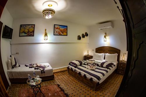a hotel room with two beds and a table at Riad Hikaya - Fes Story in Fès