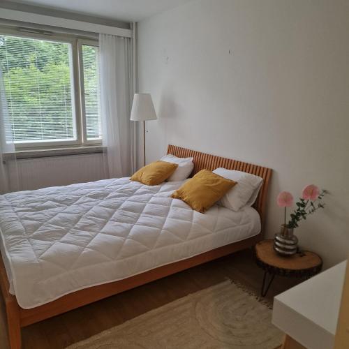 a bedroom with a bed with white sheets and a window at Porvoo Central Apartment in Porvoo