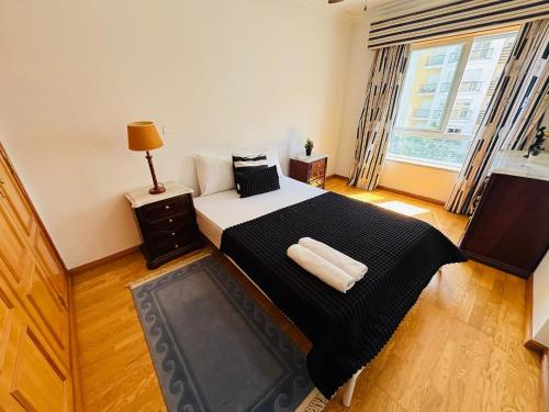 a bedroom with a bed with a black blanket and a window at Luxury apartment next Lisbon centre, super well connected in Queluz