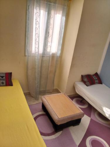 a room with a bed and a table and a window at Dar ELHAJ in Tozeur