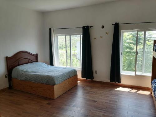 a bedroom with a bed and two windows at Cabaña con picina Panorámica in Tonalá