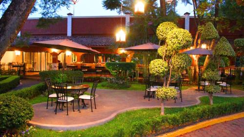 un patio con mesas, sillas y sombrillas en Meson del Valle, en Zamora de Hidalgo