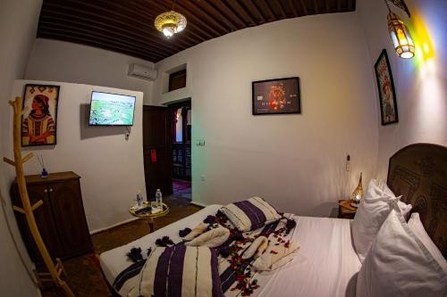 a bedroom with a bed and a tv on the wall at Riad Hikaya - Fes Story in Fès