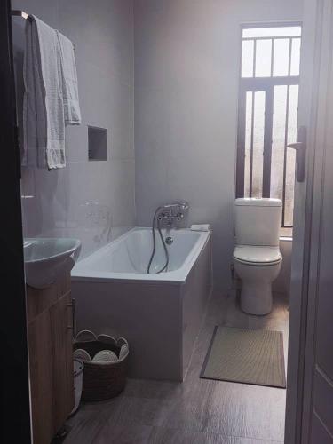 a bathroom with a tub and a toilet and a sink at Kuwunda Apartments in Lusaka